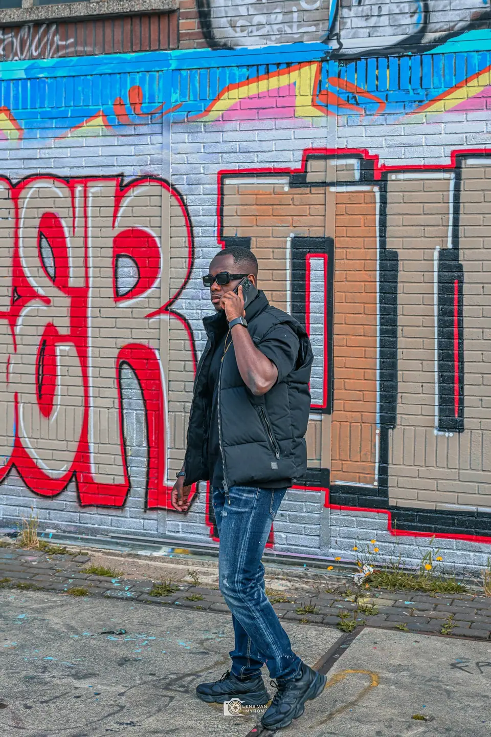 Gitoo belt, lopend langs een muur met grote rode en blauwe graffiti.
